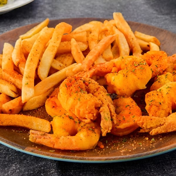 A plate of golden-brown fried shrimp and seasoned french fries from Made Burgers.