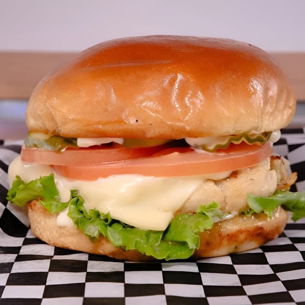 Made Burgers' chicken burger with melted cheese, lettuce, tomato, and pickles on a brioche bun.