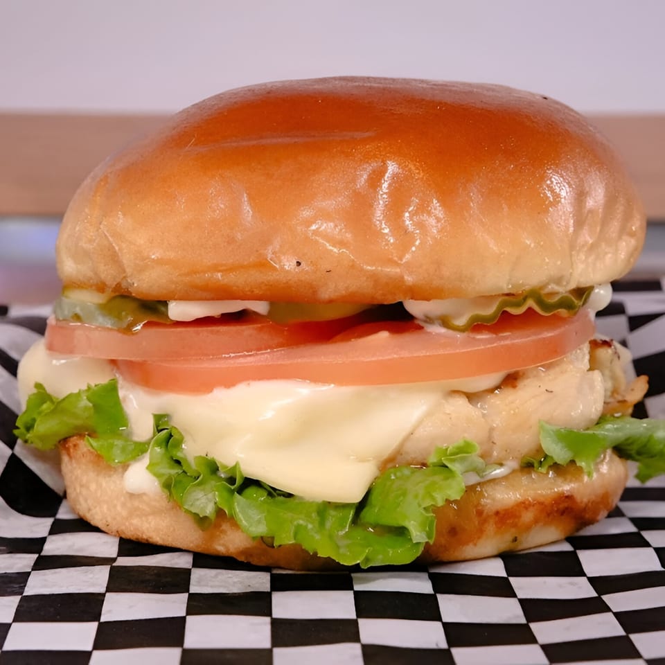 Made Burgers' chicken burger with melted cheese, lettuce, tomato, and pickles on a brioche bun.