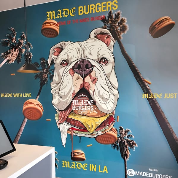 Made Burgers wall art featuring a bulldog eating a burger, palm trees, and floating burgers.