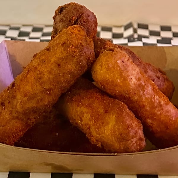 Golden brown fried corn dog bites piled in a cardboard tray from Made Burgers.