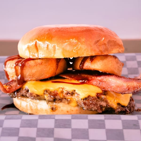 Made Burgers' burger with bacon, melted cheese, onion rings, and barbecue sauce on a bun.