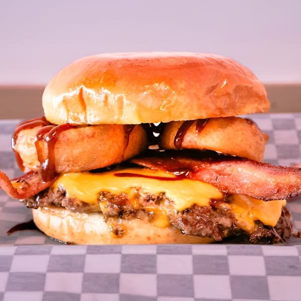 A Made Burgers burger with a beef patty, melted cheese, bacon, onion rings, and BBQ sauce.